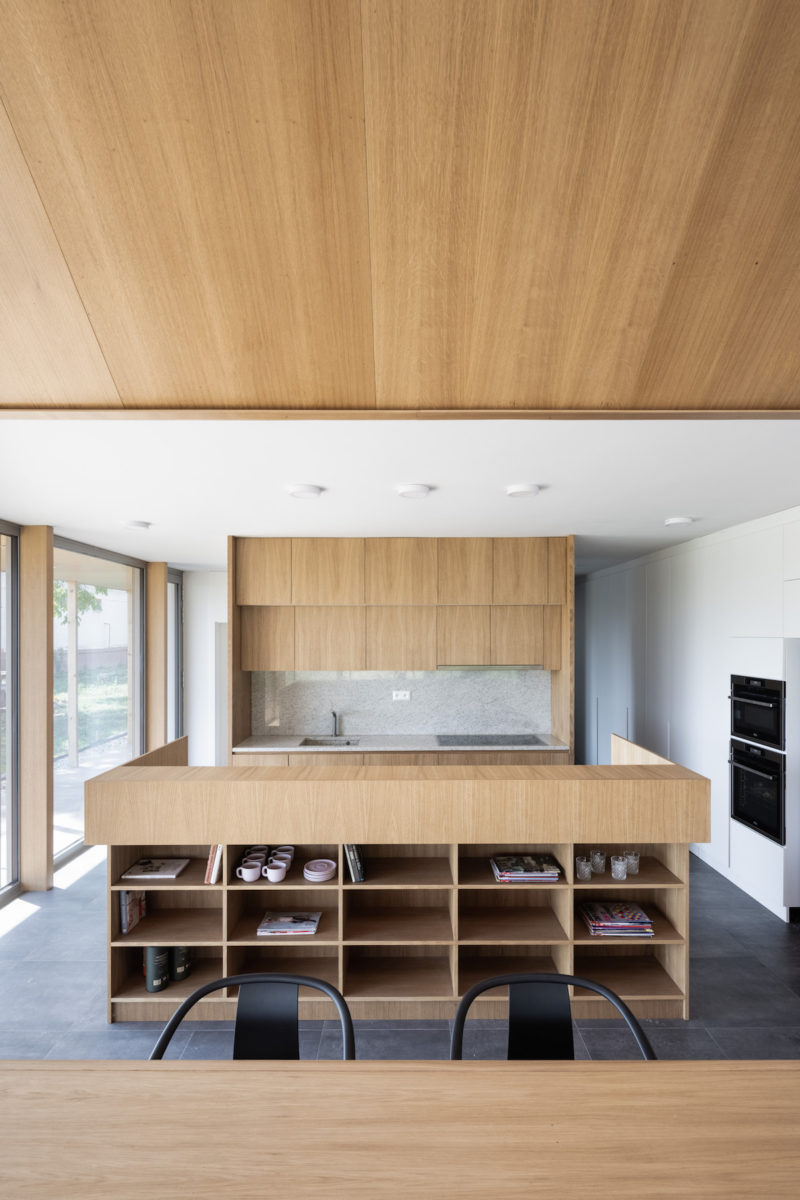 Dřevěná moderná kuchyň s výhledem cez prosklení do zahrady