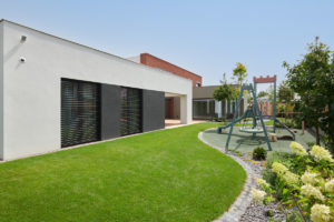 Moderní vila s velkým prosklením a zahradou s dětským hřištěm