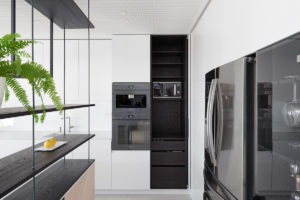 Bílá velká moderní kuchyň s černými spotrebiči ve vile