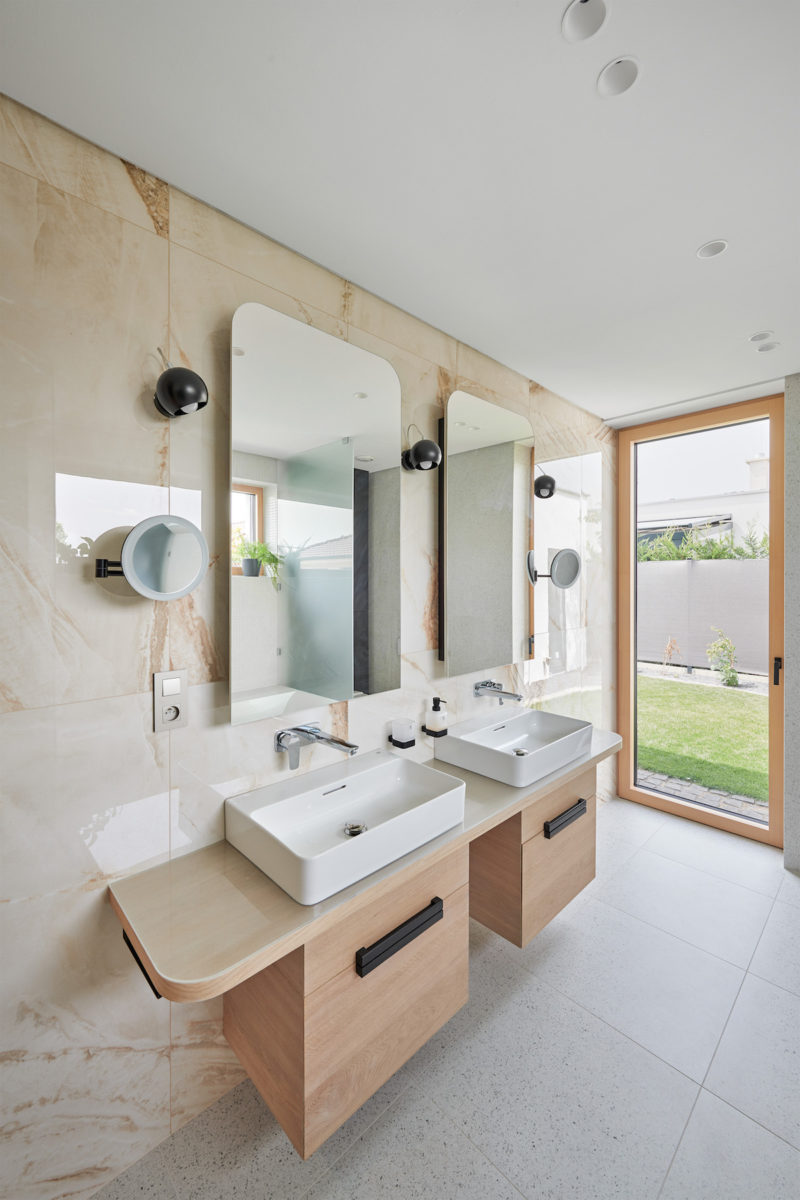 Moderní svetlě mramorová koupelna s oblými zrcadli