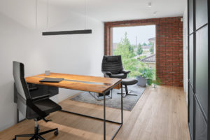 Designová pracovna s dřevěným stolem koženým křeslem a cihlovou zdí