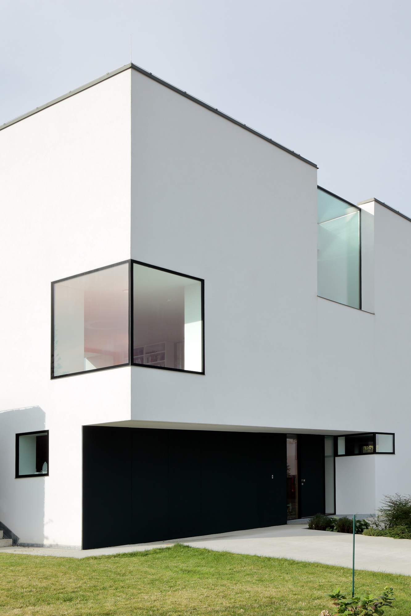 Bílý geometrický rodinný dům s velkými bezrámovými okny