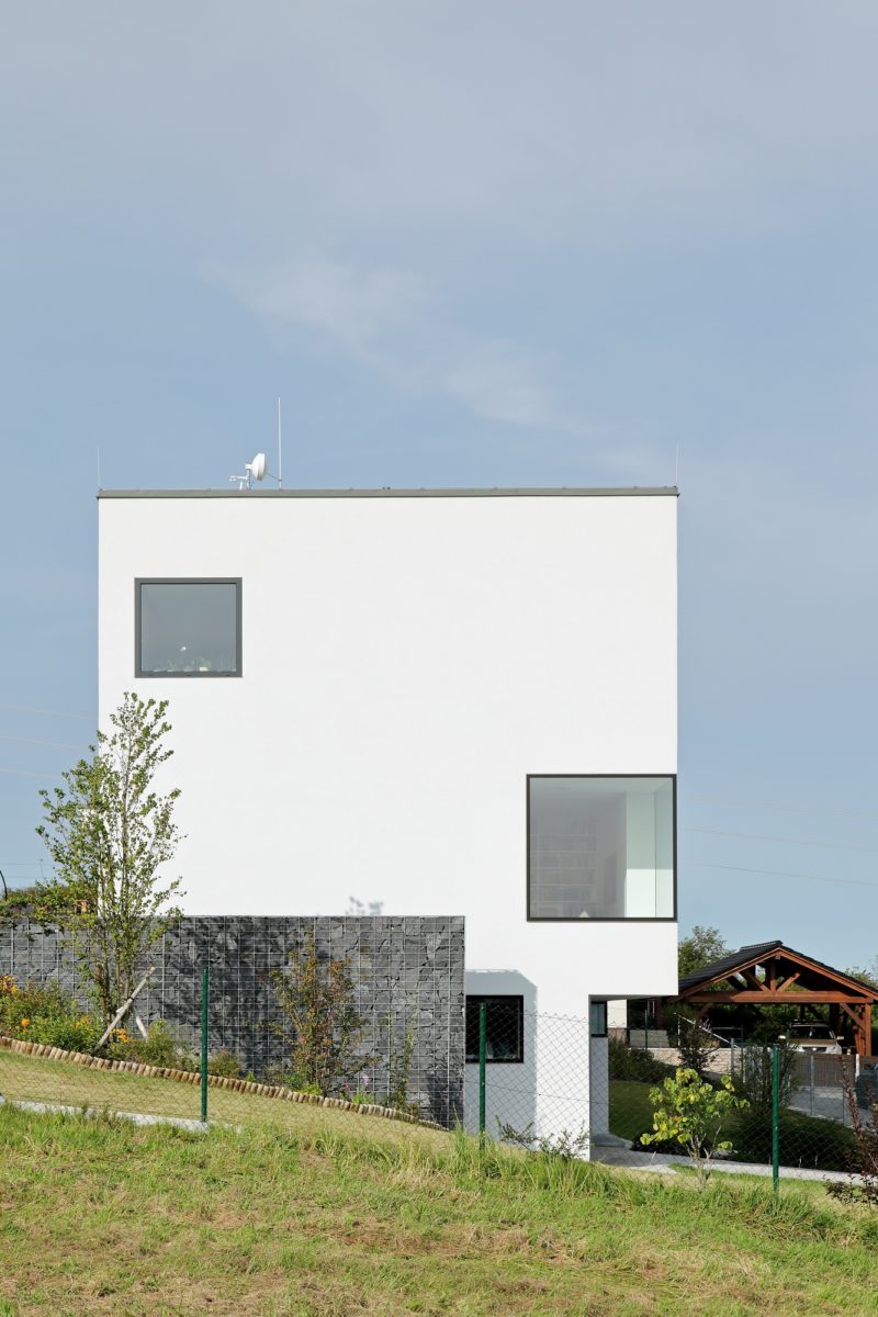 Bílý geometrický rodinný dům s velkými bezrámovými okny