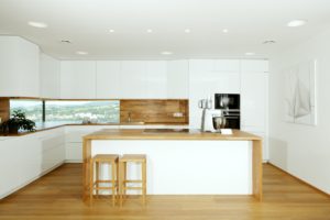 Velká bílá kuchyň s dřevěnou doskou a podlahou
