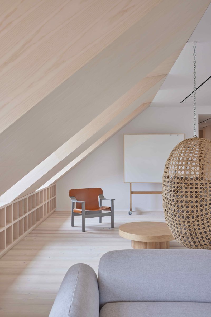 Podkrovní obývák obložen světlým dřevem se šikmou stěnou