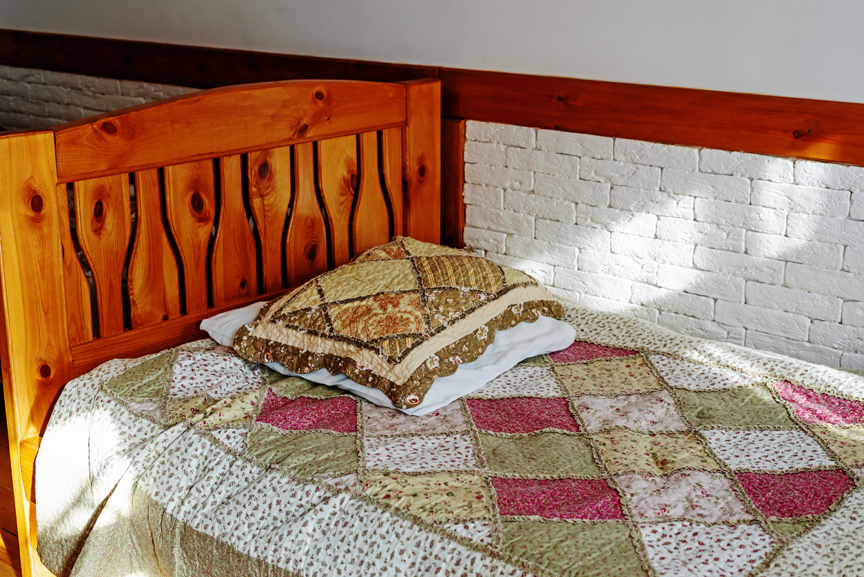 Antique wooden bed with blanket and pillows in country house
