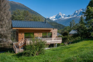 Alpská hranatá chata s velkým oknem obložená modřínem
