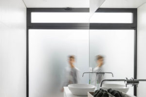 Bílá koupelna se skleněnou stěnou a dřevěnou podlahou