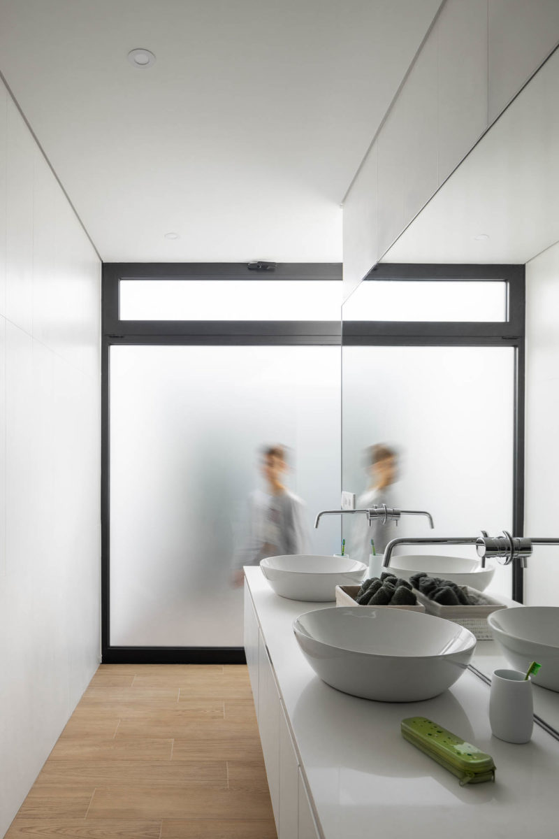 Bílá koupelna se skleněnou stěnou a dřevěnou podlahou
