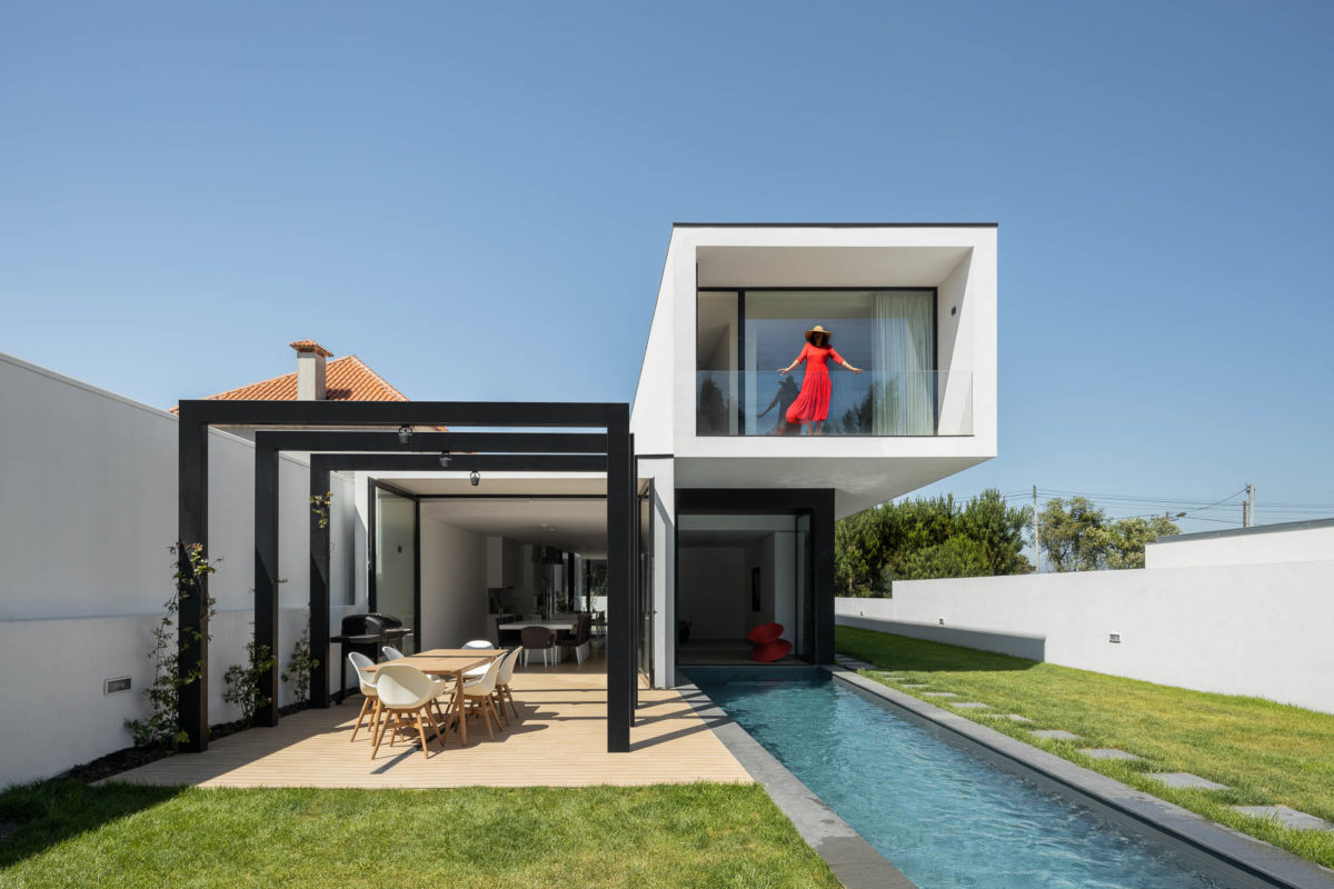 Dvoupodlažní hranatý černobílý dům s dlouhým bazénem