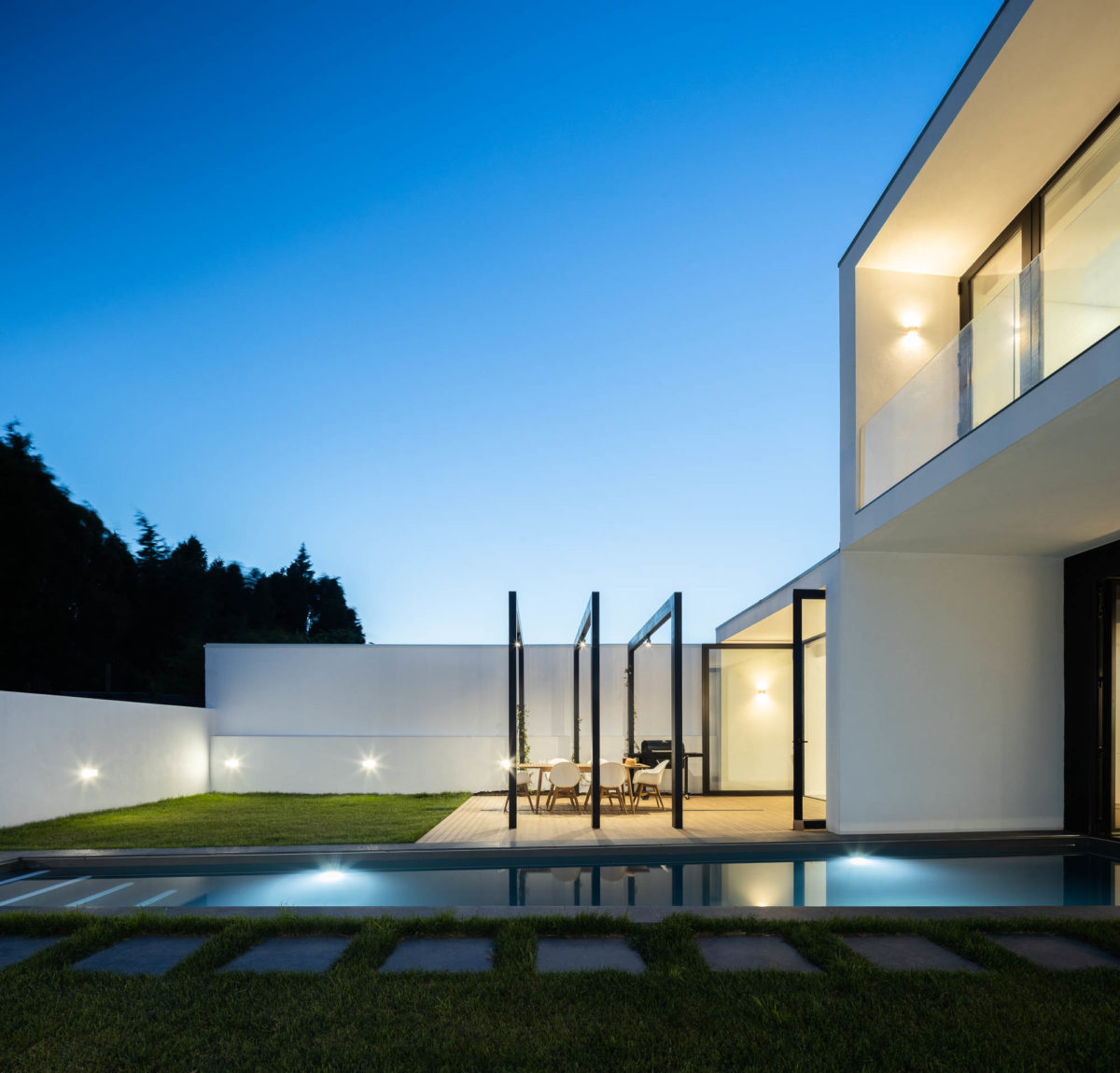 Dvoupodlažní hranatý černobílý dům s dlouhým bazénem