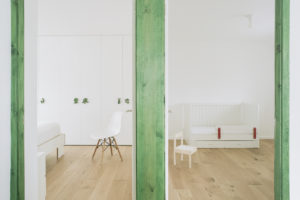 Bílý interiér bytu se zelenými rámy a obkladem