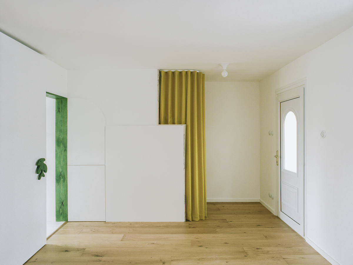 Bílý interiér bytu se zelenými rámy a žlutým závěsem