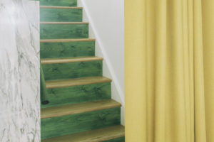 Bílý interiér bytu se zeleným schodištěm