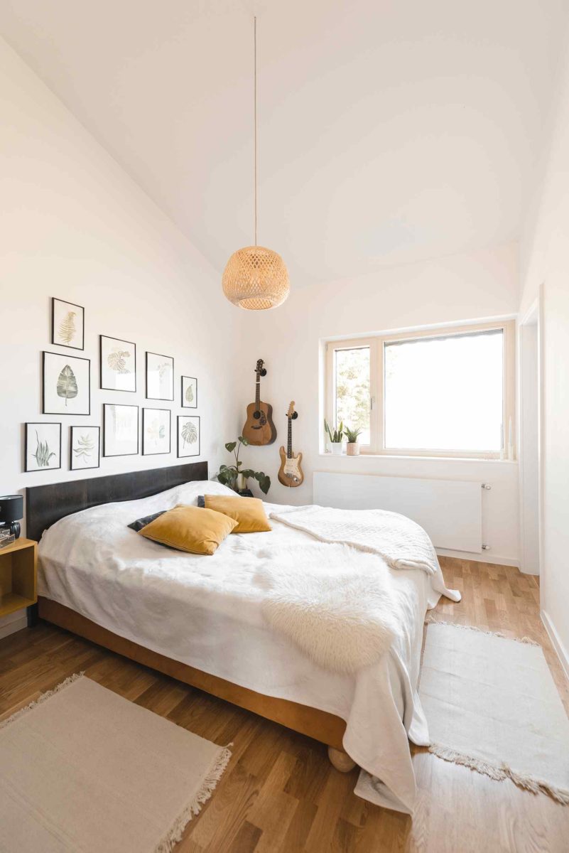 Jednoduchá ložnice s dřevěnou podlahou a ratanovým svítidlem