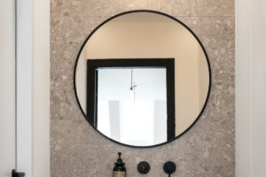 Minimalistická koupelna s velkým okrouhlým zrcadlem