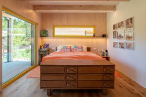 Dřevěná ložnice s komodou a oranžovým povlečením