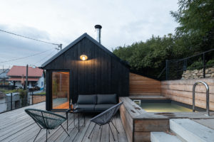 Tradiční víkendový dům ve svahu s moderní tmavou přístavbou s bazénem na terase