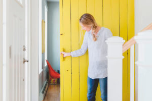 Žena zatevírá žluté dveře