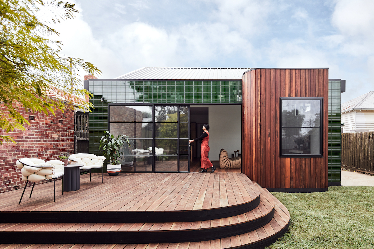 Malý ekologický moderní domeček geometrických tvarů se zeleným a hnědým obkladem