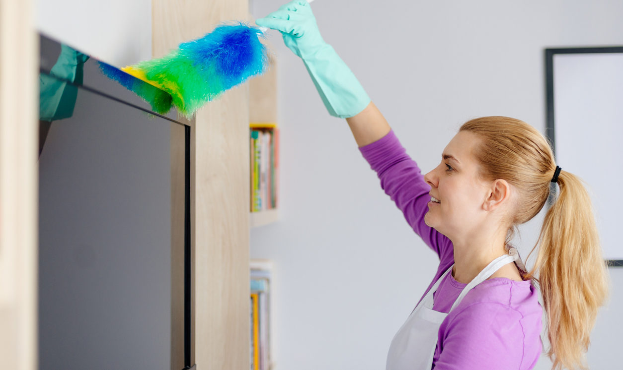 Young beautiful woman in white apron cleaning tv