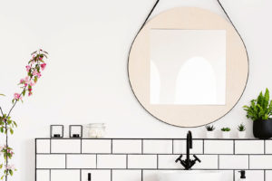Černá koupelnová skříňka s umyvadlem, kulatým zrcadlem a bílými obklady