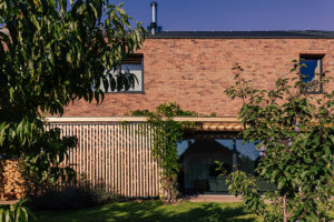 Červená cihlová fasáda a dřevěná pergola - Rodinný dům s veterinou v Plzni