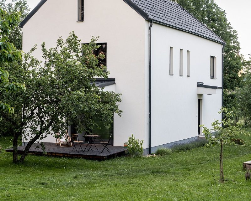 Tradiční dům v bílé s grafitovou střechou v přírodě