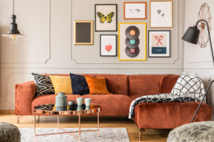 Eklektický interiér obývacího pokoje s pohodlnou sametovou rohovou pohovkou s polštáři