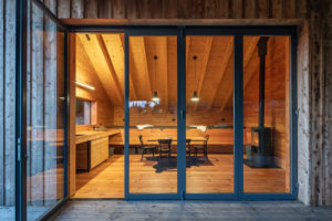 Společenský prostor s kuchyní a obývací částí s velkým prosklením a krbovými kachlemi - Chalupa bez technologií v Orlických Horách