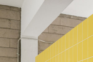 Žluté keramické obklady a betónová stěna - Dům MG08 v Madridu