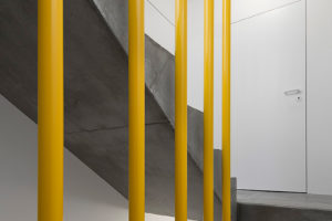 Žluté zábradlí schodiště - Třípodlažní přístavba v Praze