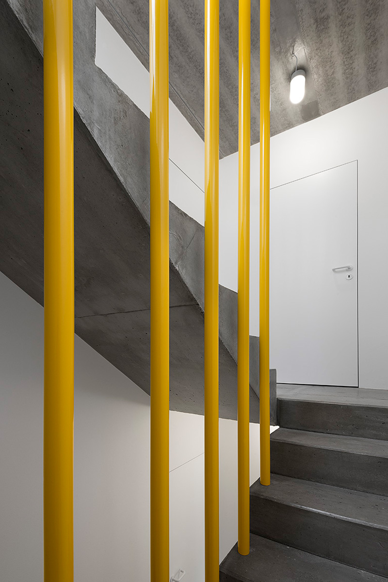 Žluté zábradlí schodiště - Třípodlažní přístavba v Praze