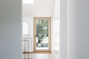 Bílá chodba zakončená dveřmi do zahrady -Třešňový dům