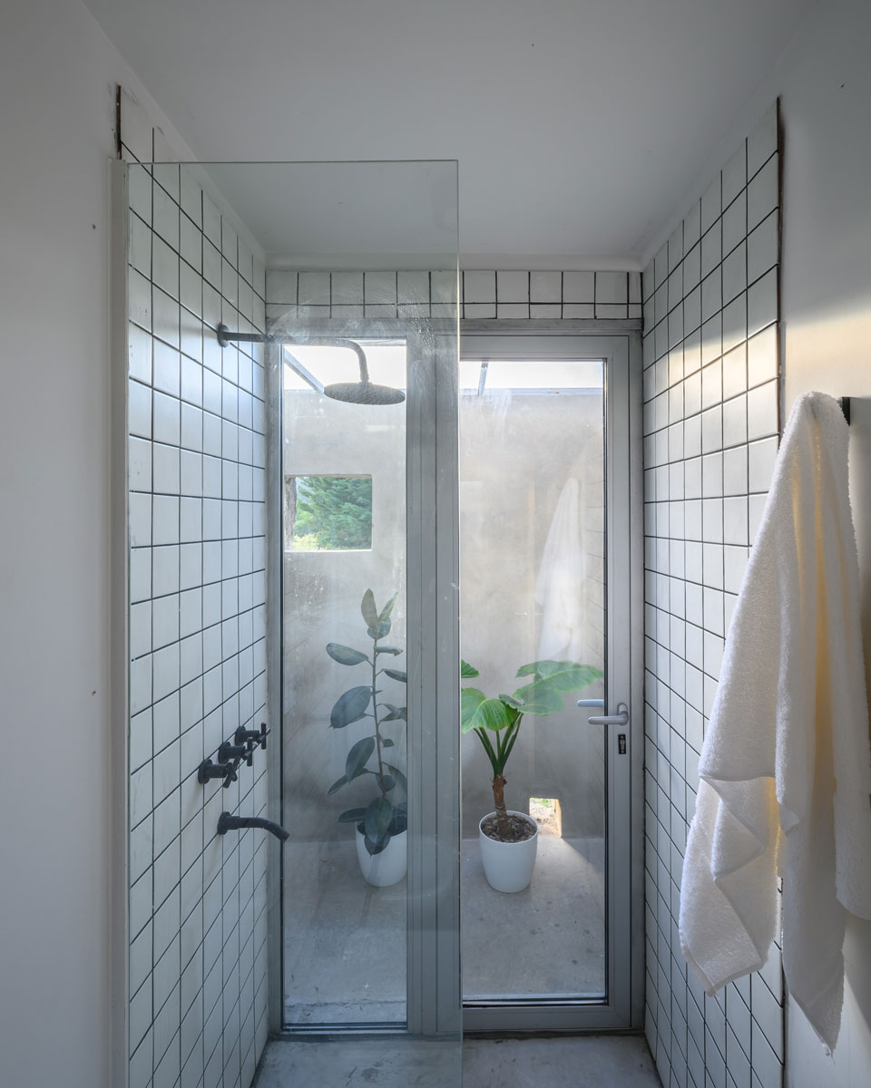 Koupelna se skleněnými dveřmi a rostlinami v bílých květináčích -Modulární domek