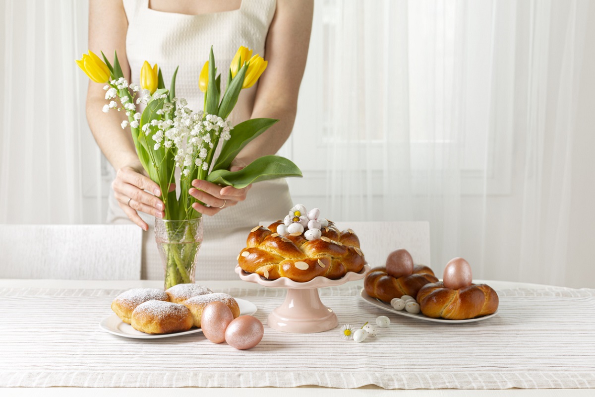 stůl s velikonočním pečivem, vejci, bonbóny a jarními květinami