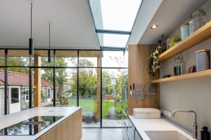 Světlý a vzdušný kuchyňský interiér s vysokými stěnami a střešním oknem.
