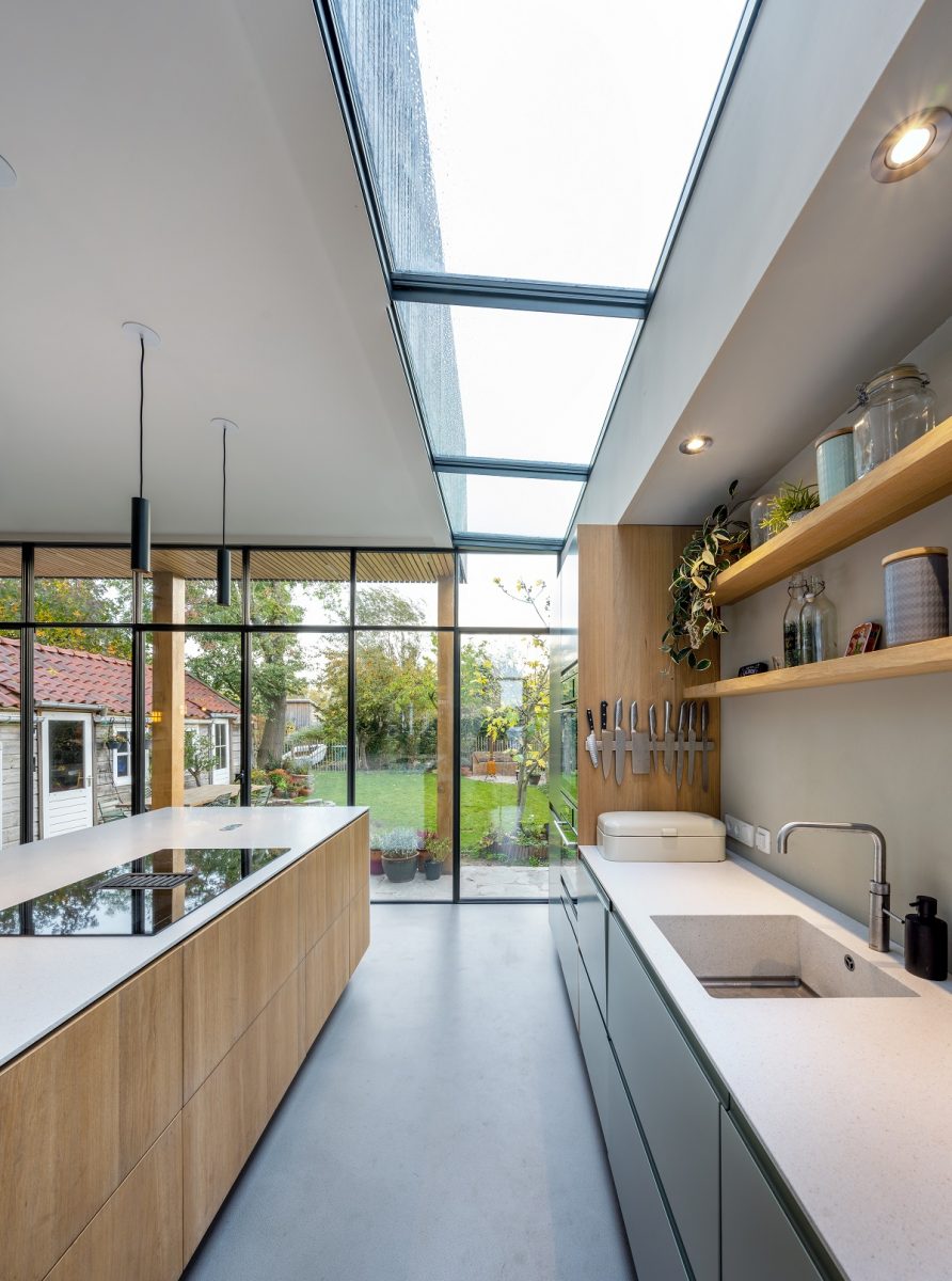 Světlý a vzdušný kuchyňský interiér s vysokými stěnami a střešním oknem.