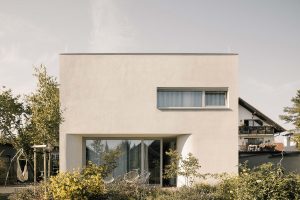 Dvouposchoďový bílý dům kompaktního tvaru se zahradou