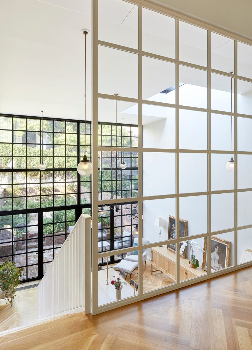 Moderní interiér s velkými skleněnými okny, kterými proniká přirozené světlo.