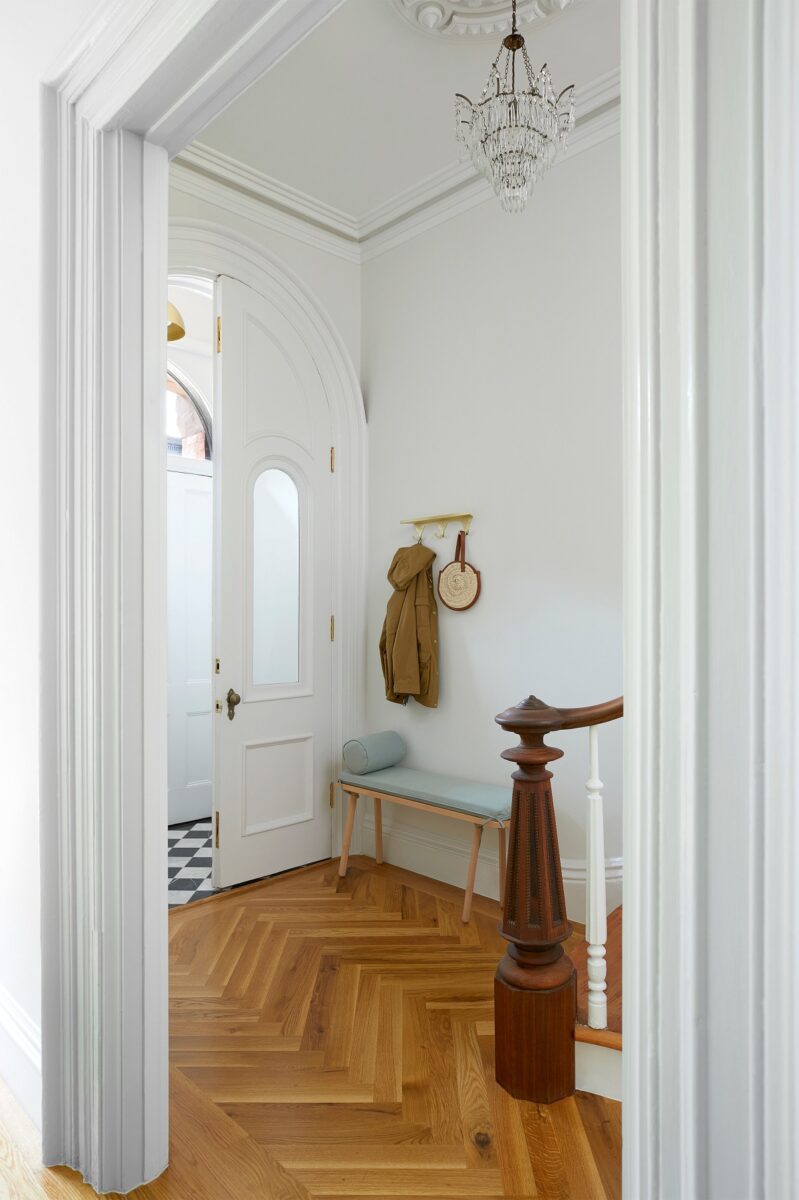 Bílé vstupní dveře a dřevěná lavice vytvářejí elegantní a příjemný vstupní prostor.