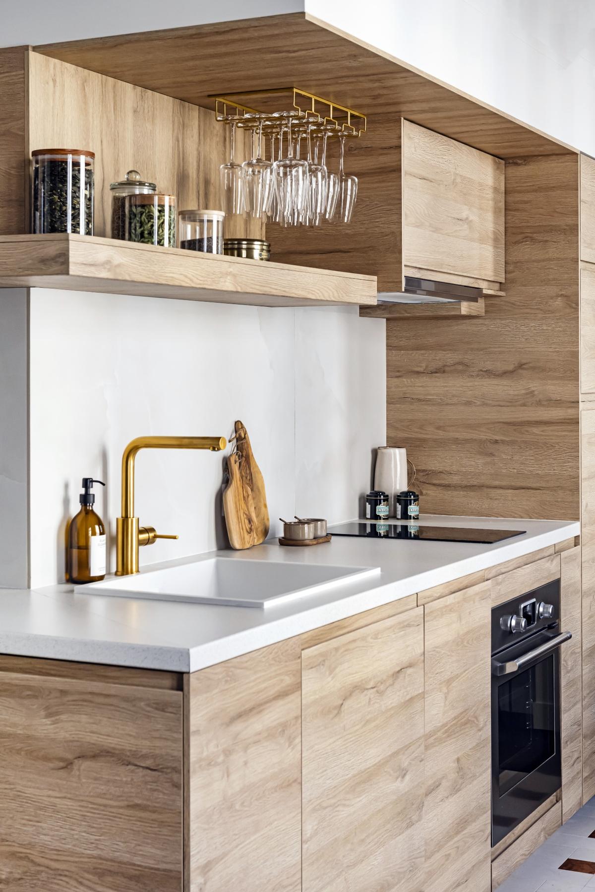 Moderní kuchyň s dřevěným obložením, bílou pracovní deskou.