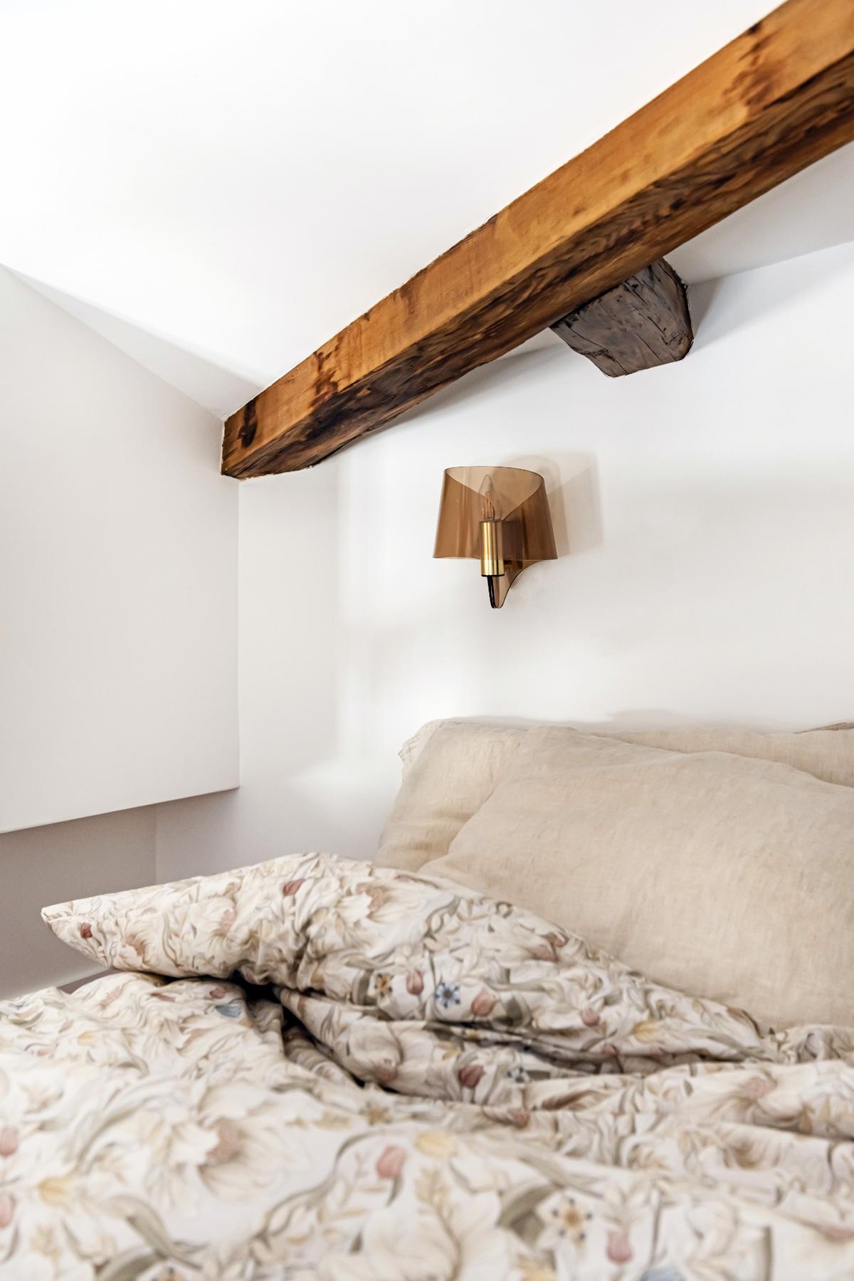 Ložnice s dřevěným trámem na stropě