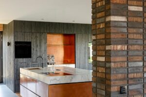 Tato moderní kuchyně se vyznačuje výrazným mramorovým ostrůvkem a teplými dřevěnými skříněmi, což spojuje luxus s přírodními materiály.