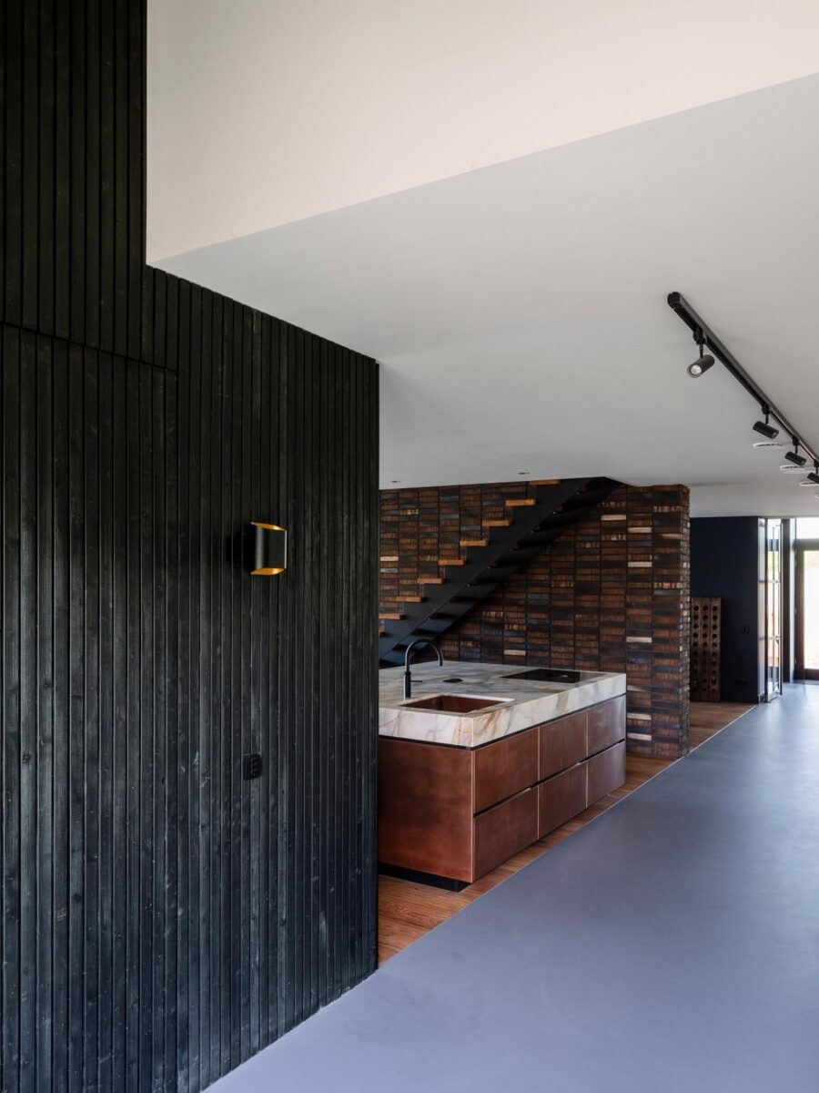 Moderní kuchyně s černými stěnami a mramorovým ostrůvkem.
