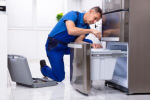 Mature,Male,Serviceman,Repairing,Refrigerator,With,Toolbox,In,Kitchen