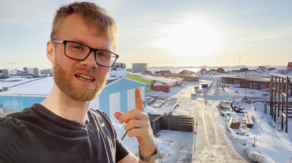 Alex na balkoně. Za zády má centrum Nuuku a fjord.