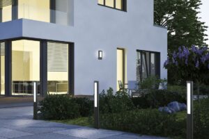 Moderní LED sloupkové osvětlení podél cestičky v zahradě před minimalistickým rodinným domem.