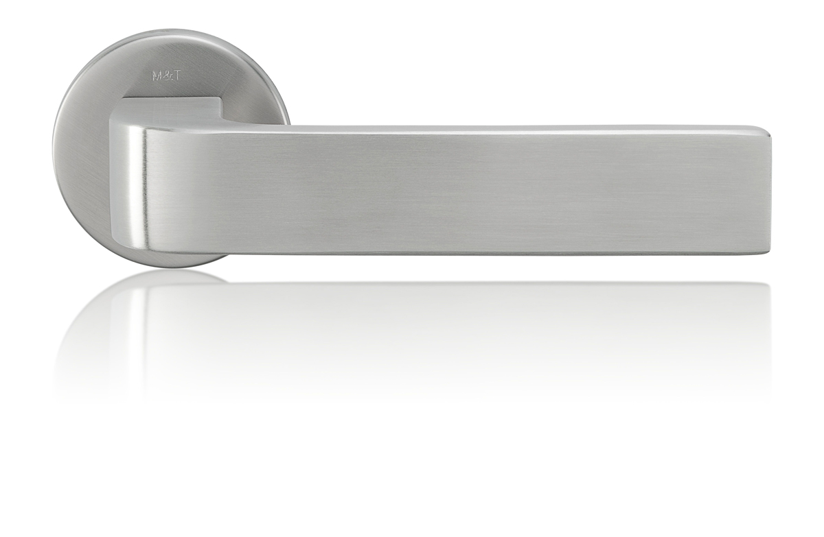 Detailní pohled na moderní dveřní kliku z matné nerezové oceli s minimalistickým designem a jemným odleskem, na bílém neutrálním pozadí.