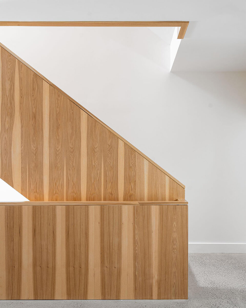Detail schodiště obloženého světlým dřevem ve svěžím minimalistickém interiéru
